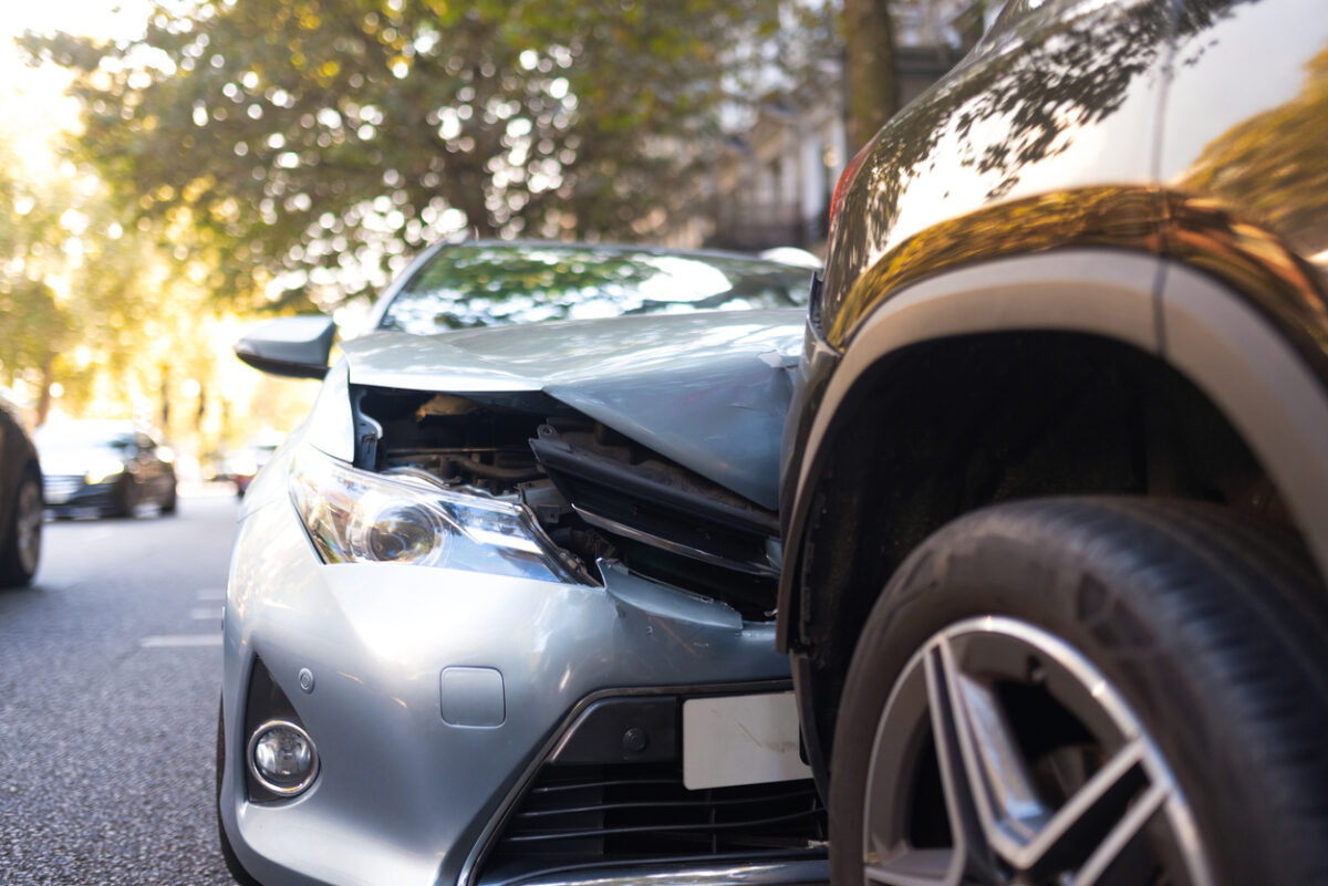Two damaged vehicles in car accident after collision on city street. Road safety and insurance concept